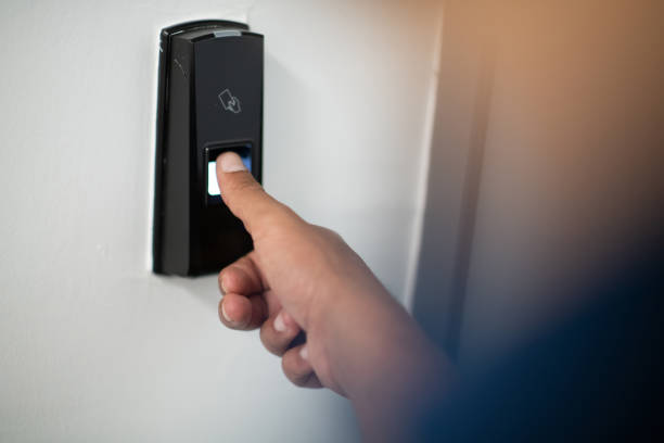 Man pressing fingerprint scanner on alarm system indoorsFinger print scan for unlock door security system. High-quality photo