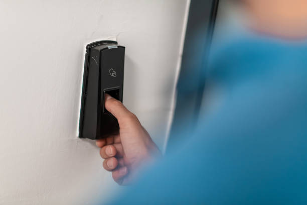 Man pressing fingerprint scanner on alarm system indoorsFinger print scan for unlock door security system. High-quality photo